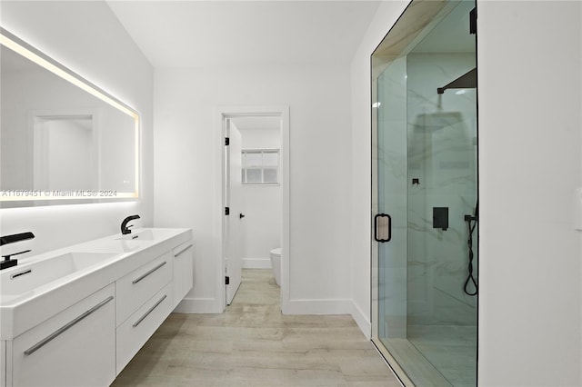 bathroom featuring a shower with door, vanity, wood-type flooring, and toilet