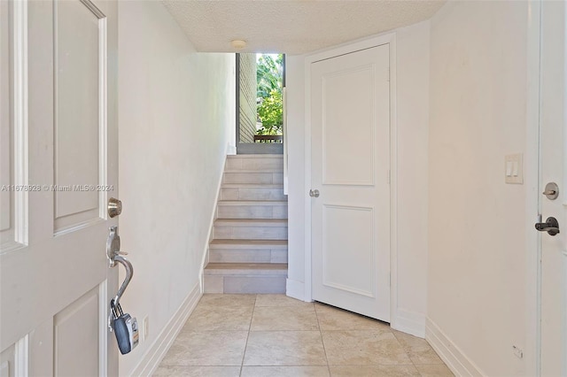 foyer with a textured ceiling and light tile patterned flooring