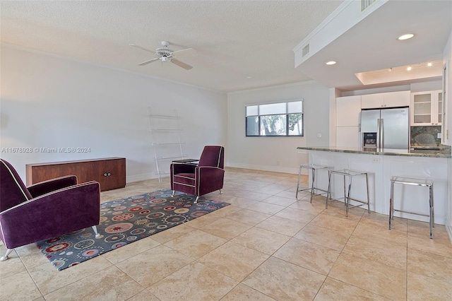 sitting room with ornamental molding, light tile patterned flooring, a textured ceiling, and ceiling fan