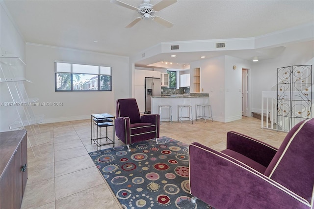 tiled living room featuring ornamental molding and ceiling fan