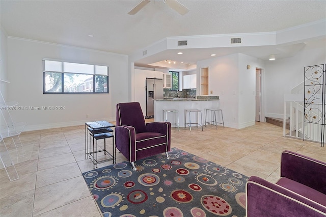 tiled living room with ornamental molding, a textured ceiling, and ceiling fan