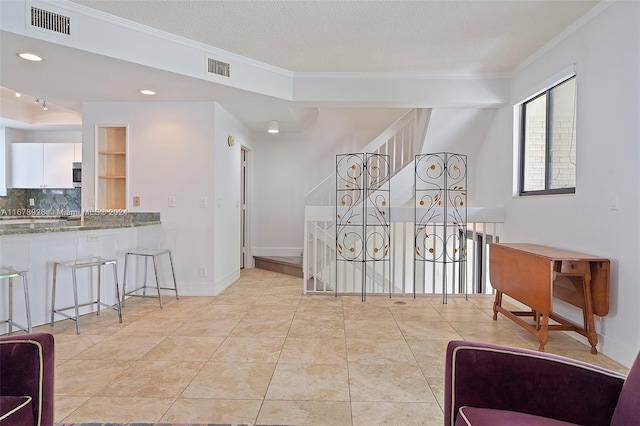 hall with crown molding, a textured ceiling, and light tile patterned flooring