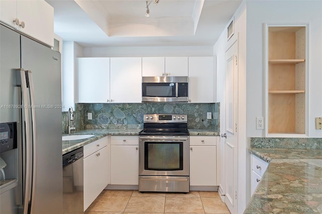 kitchen featuring decorative backsplash, stainless steel appliances, light stone countertops, a raised ceiling, and white cabinets