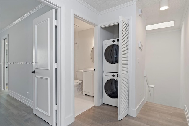 washroom featuring light hardwood / wood-style flooring, ornamental molding, and stacked washer and clothes dryer