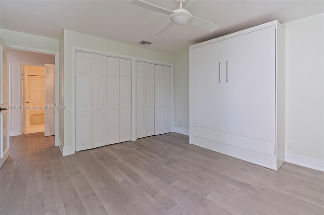 unfurnished bedroom featuring light hardwood / wood-style flooring, multiple closets, and ceiling fan