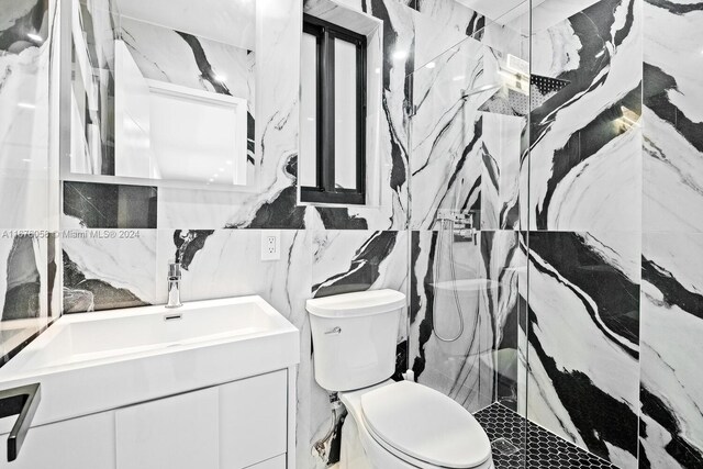 bathroom with tiled shower, toilet, tile walls, and vanity