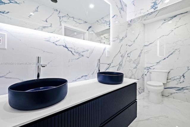 bathroom with vanity, toilet, and tile walls