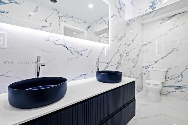 2340 NE 194th St, Miami, FL 33180 - bathroom featuring stone wall, vanity, toilet, marble tiled floors, and tile walls