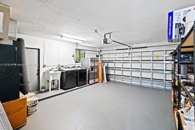 garage featuring washing machine and dryer, stainless steel fridge with ice dispenser, sink, and a garage door opener