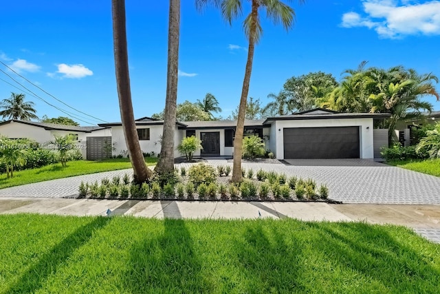 2340 NE 194th St, Miami, FL 33180 - view of front of house featuring stucco siding, a garage, decorative driveway, and a front lawn