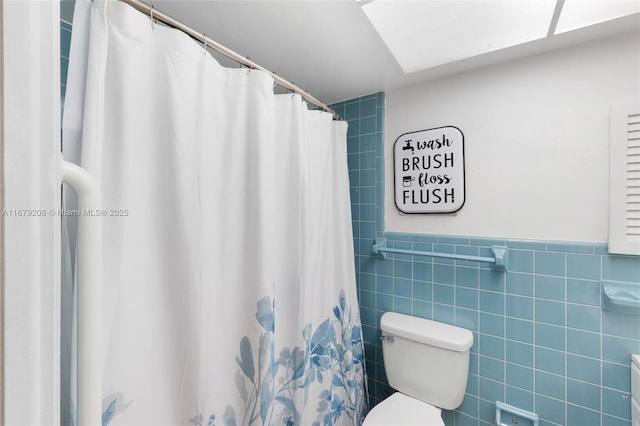 bathroom featuring a shower with curtain, toilet, and tile walls