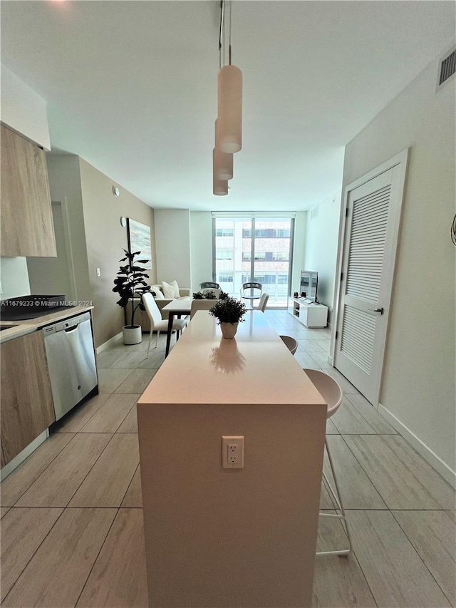 kitchen with light tile patterned floors, a kitchen breakfast bar, floor to ceiling windows, dishwasher, and pendant lighting