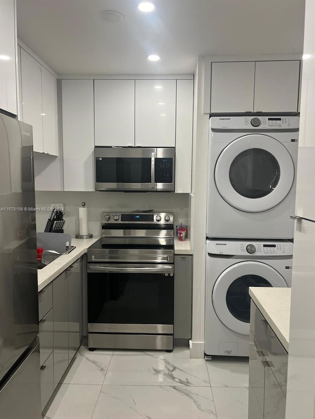 kitchen with gray cabinets, white cabinetry, stainless steel appliances, and stacked washer / dryer