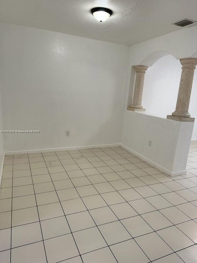 unfurnished room with light tile patterned flooring and a textured ceiling