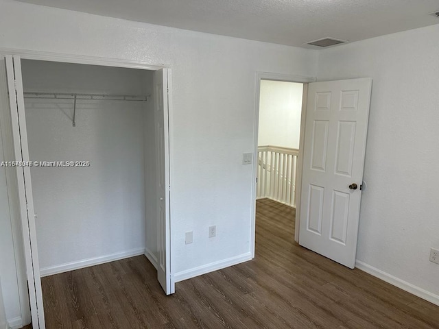 unfurnished bedroom with dark hardwood / wood-style flooring and a closet