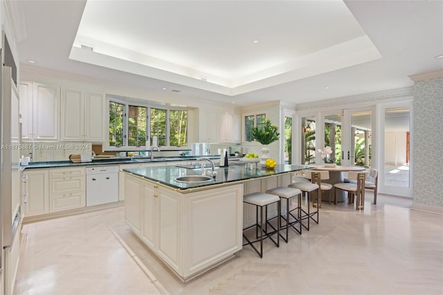 kitchen featuring a center island with sink, sink, light parquet flooring, a raised ceiling, and dishwasher