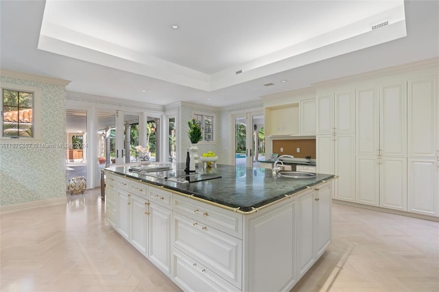 kitchen with a kitchen island with sink, a wealth of natural light, white cabinetry, and black electric cooktop