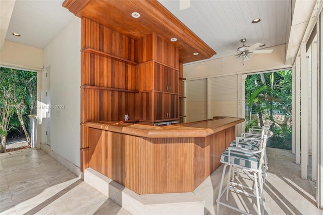 bar featuring a wealth of natural light, ceiling fan, and wooden walls