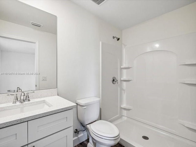 bathroom featuring toilet, walk in shower, and vanity