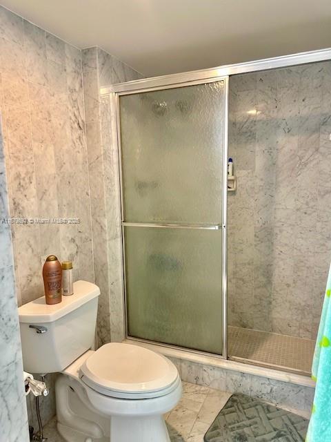 2301 S Ocean Dr Unit A8, Hollywood, FL 33019 - full bathroom featuring toilet, a shower stall, and tile walls