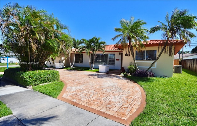 view of front of house featuring a patio, cooling unit, and a front lawn