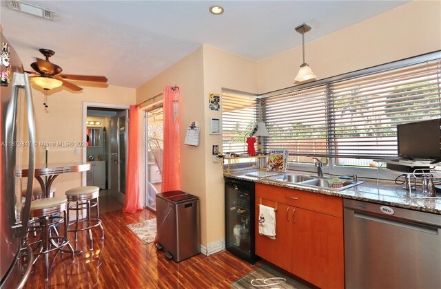 kitchen featuring sink, dark hardwood / wood-style flooring, hanging light fixtures, stainless steel dishwasher, and beverage cooler