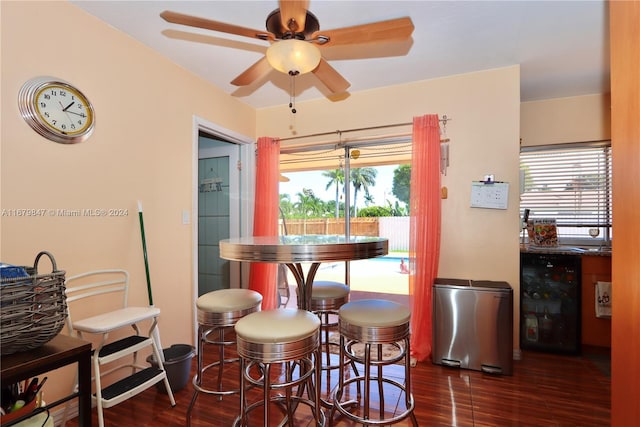 dining space featuring bar area, dark hardwood / wood-style floors, beverage cooler, and a wealth of natural light