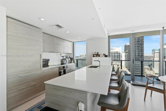 kitchen featuring a breakfast bar, a wealth of natural light, and a center island with sink