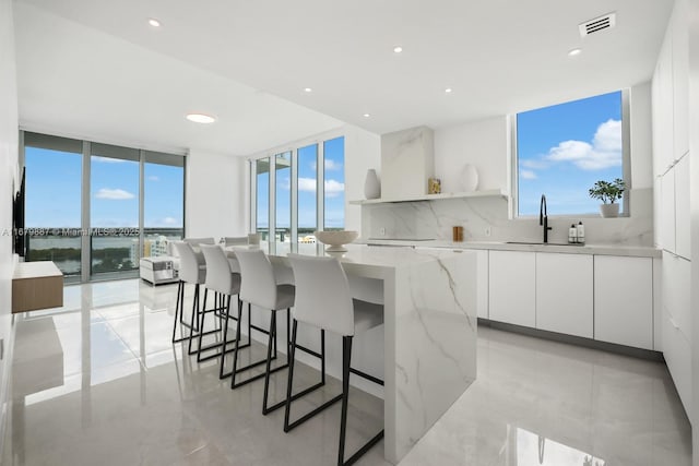 kitchen with light stone counters, white cabinets, a center island, open shelves, and modern cabinets