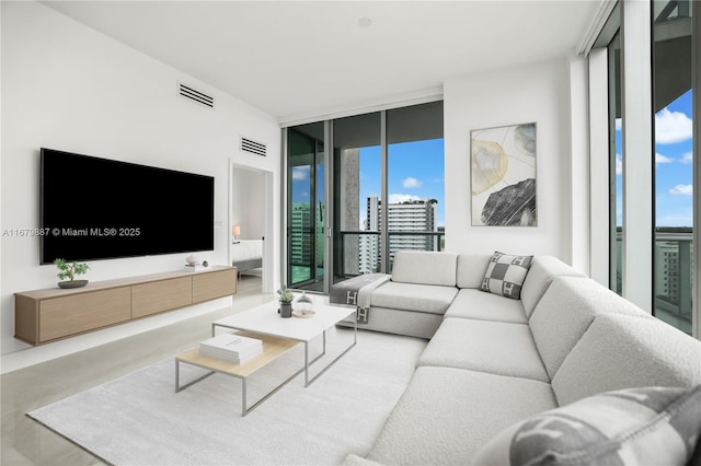 living room with visible vents, a wall of windows, and a city view