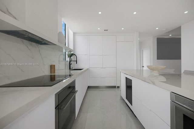 kitchen with black appliances, modern cabinets, a sink, and white cabinets