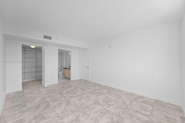 unfurnished bedroom featuring a closet, a walk in closet, and ensuite bath