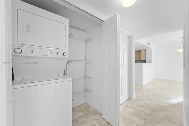 laundry area with stacked washer / dryer and light tile patterned floors