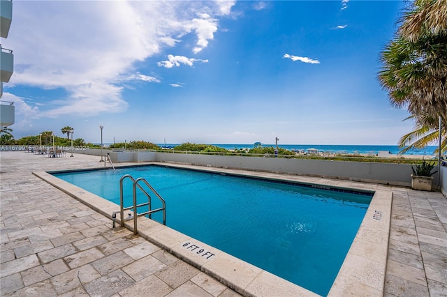 view of pool featuring a patio area and a water view