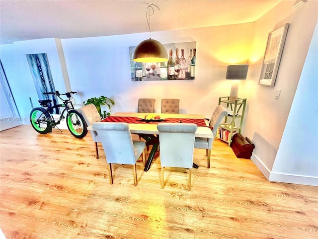 dining space featuring light wood-type flooring and baseboards