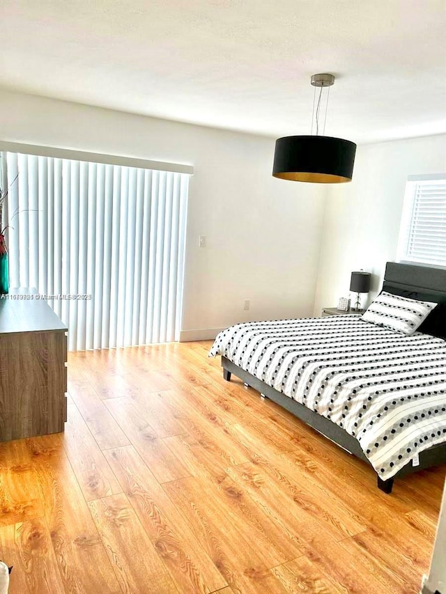 bedroom with multiple windows, baseboards, and wood finished floors