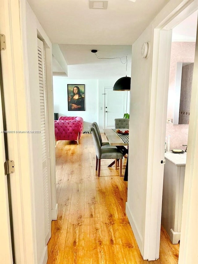 hallway featuring light wood-style flooring and baseboards