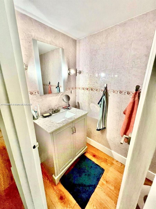 bathroom with decorative backsplash, tile walls, vanity, and wood finished floors