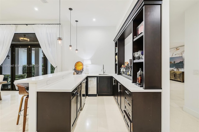 kitchen with kitchen peninsula, hanging light fixtures, a kitchen bar, and light tile patterned floors