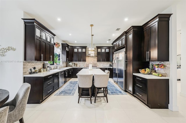 kitchen featuring sink, a center island, hanging light fixtures, stainless steel appliances, and decorative backsplash