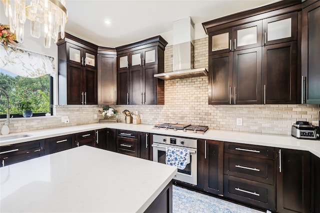 kitchen featuring decorative backsplash, sink, pendant lighting, wall chimney exhaust hood, and stainless steel appliances