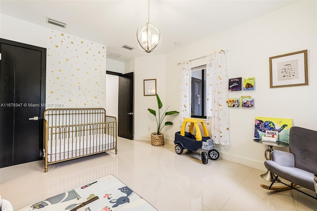 bedroom featuring a nursery area, an inviting chandelier, and tile patterned flooring