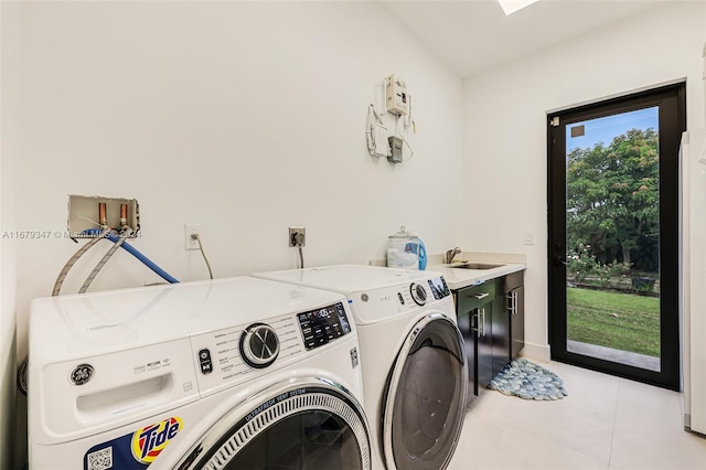 clothes washing area with sink, washer and dryer, cabinets, and light tile patterned floors