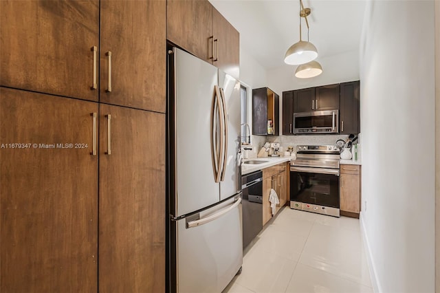 kitchen with tasteful backsplash, light tile patterned floors, appliances with stainless steel finishes, pendant lighting, and sink