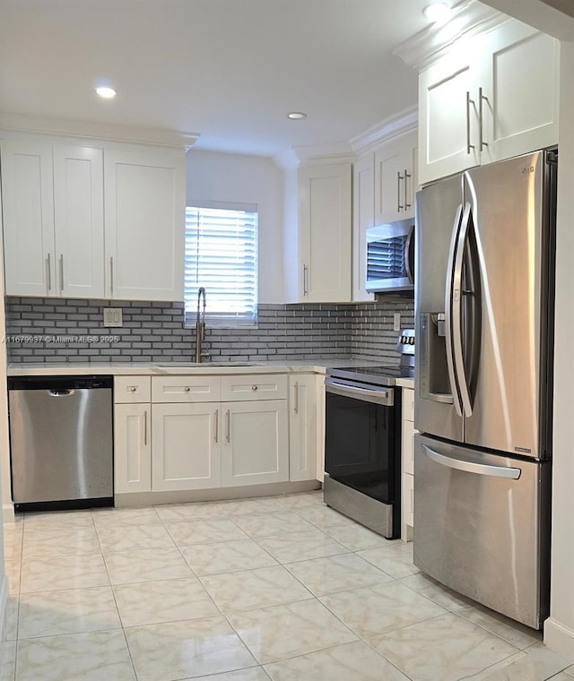 kitchen featuring decorative backsplash, white cabinets, appliances with stainless steel finishes, light countertops, and a sink