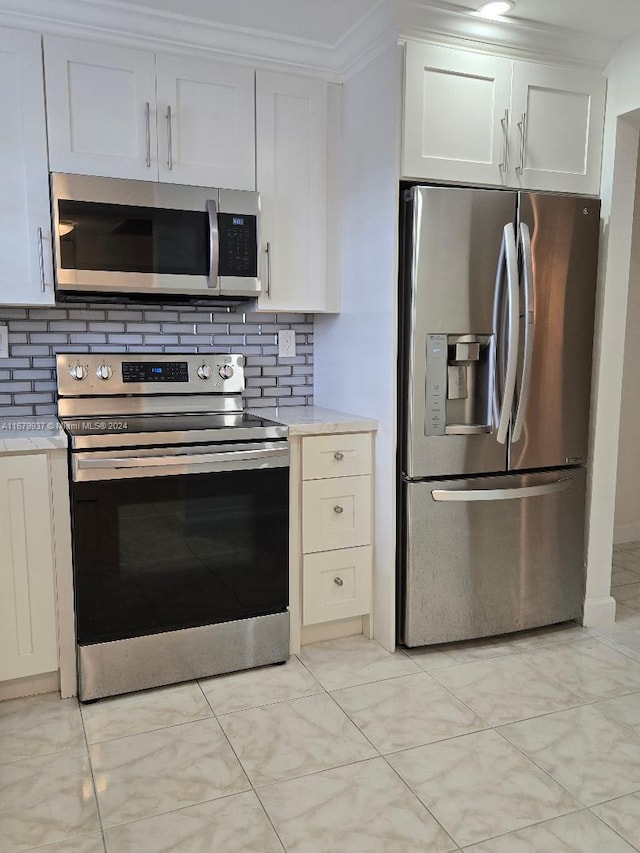 kitchen featuring backsplash, ornamental molding, appliances with stainless steel finishes, and white cabinets