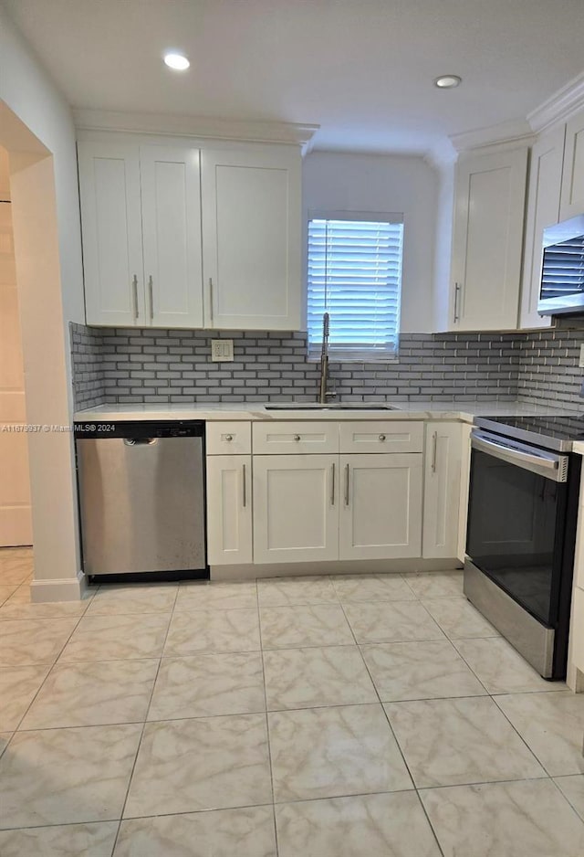 kitchen featuring stainless steel appliances, crown molding, sink, white cabinetry, and tasteful backsplash