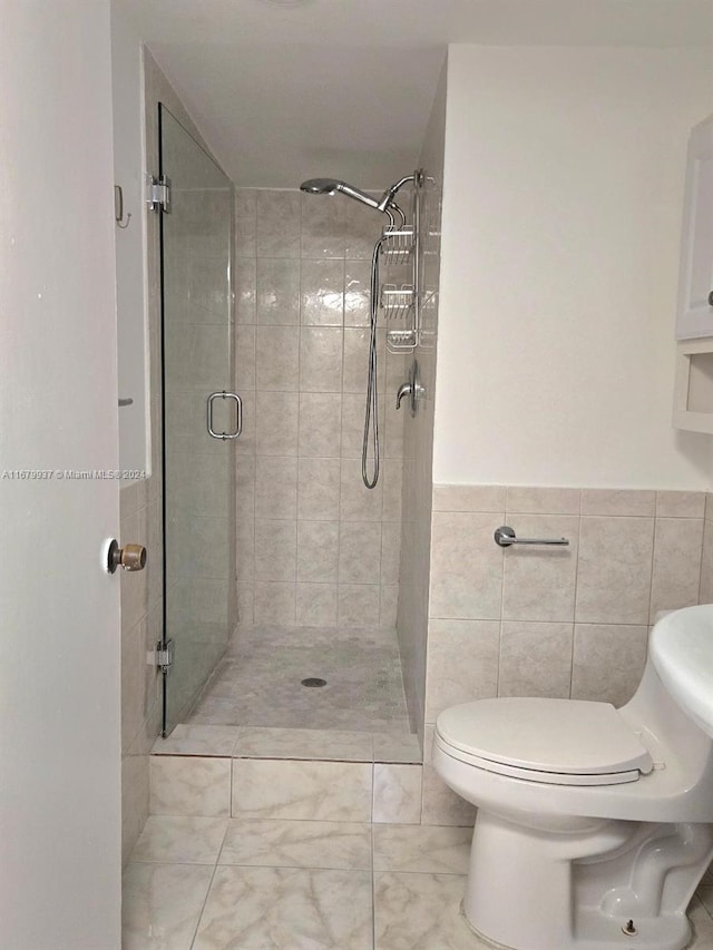 bathroom featuring toilet, tile walls, and an enclosed shower