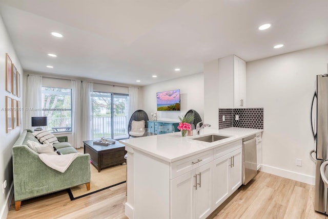 kitchen featuring appliances with stainless steel finishes, sink, kitchen peninsula, and white cabinets