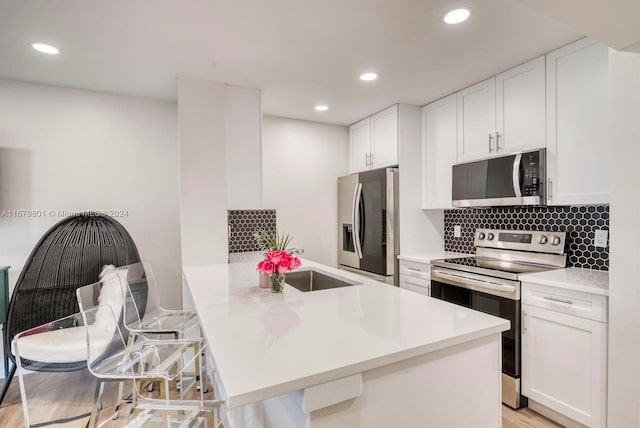 kitchen with white cabinets, kitchen peninsula, and stainless steel appliances